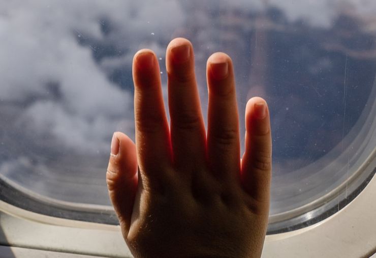 Mano di bimbo sul vetro di un aereo